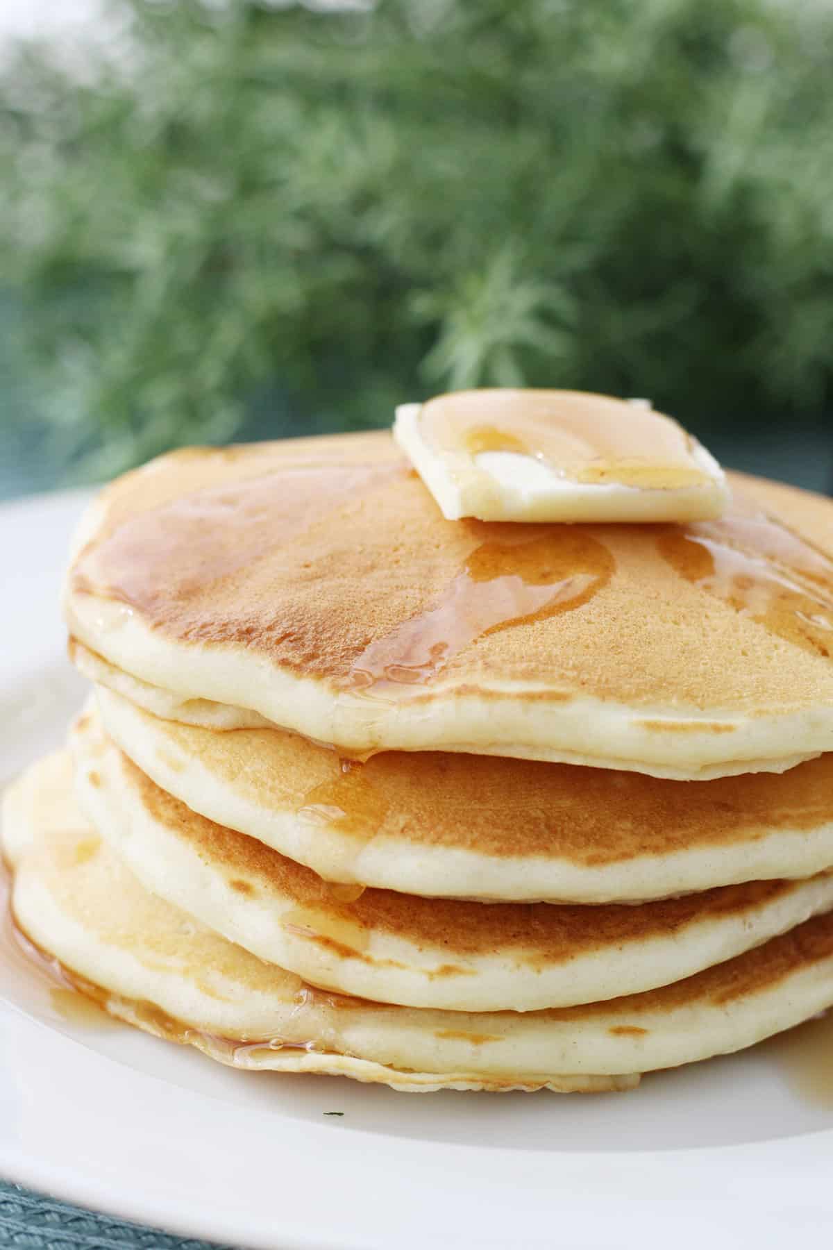 A stack of homemade pancakes on a white plate.