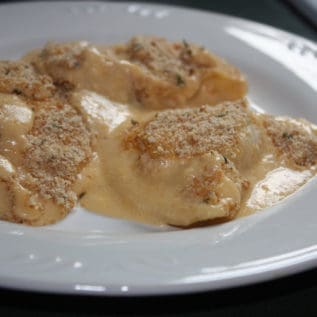 Pierogies au gratin cooked and served on a white plate