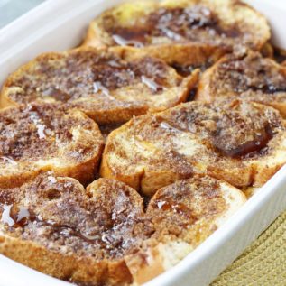 Overnight French toast casserole in a white dish on a placemat.