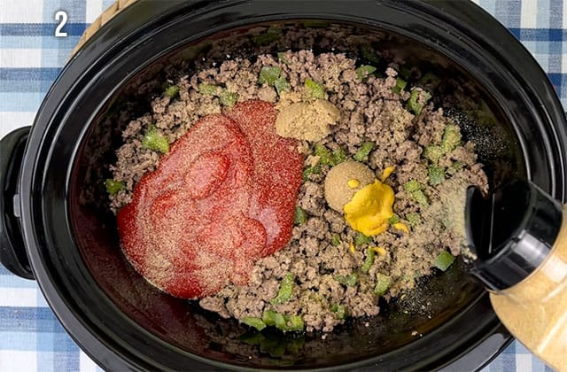 Adding ingredients for slow cooker sloppy joes into a black Crockpot