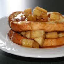 A serving of apple stuffed french toast on a white plate topped with syrup