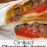 A grilled cheeseburger wrap sliced in half and sitting on a white plate