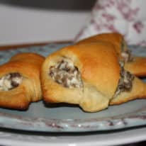 Sausage cream cheese crescent rolls on a blue plate in front of an apron