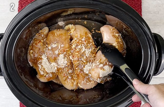 Turning chicken breasts to coat well in dressing mixture in a Crockpot