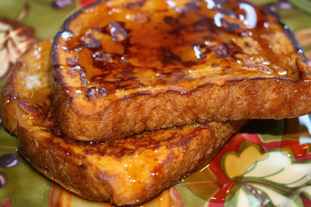 Two slices of French toast on a plate with syrup.