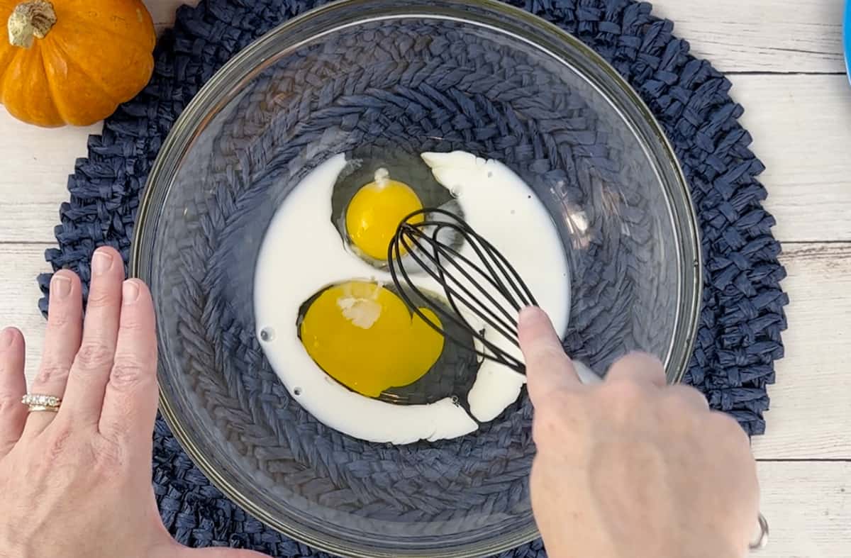 Whisking eggs and milk in a glass bowl.