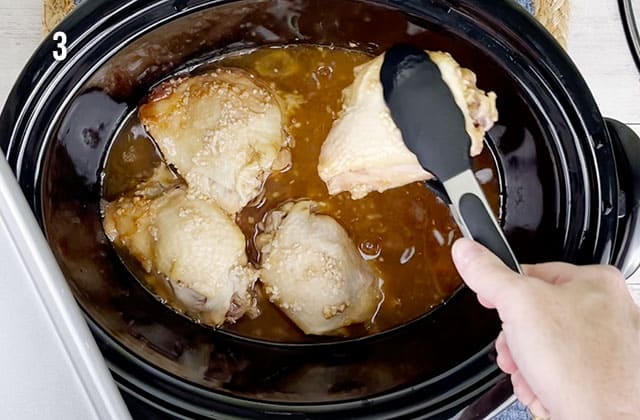 Removing slow cooker sticky chicken drumsticks from a slow cooker with black tongs
