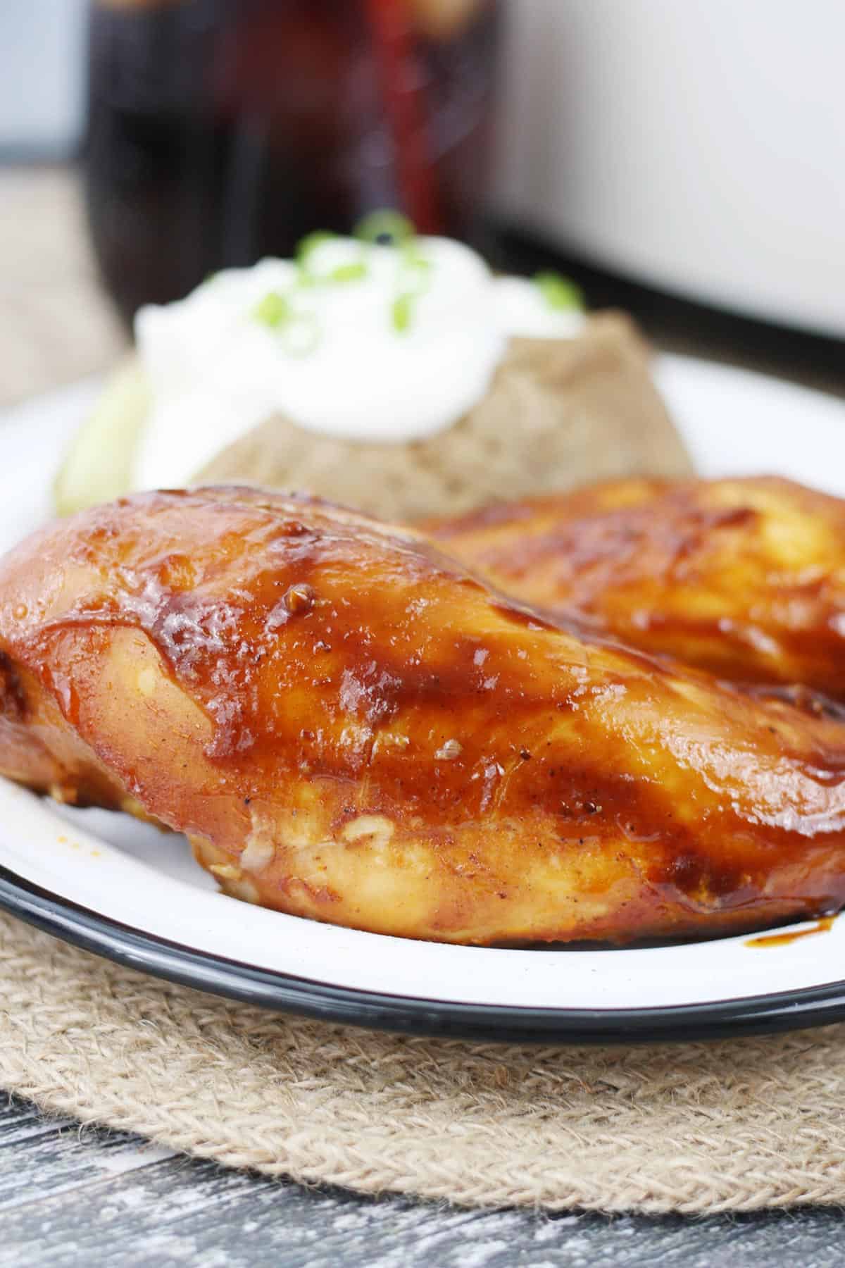 Crockpot BBQ Chicken on a white plate with a baked potato.