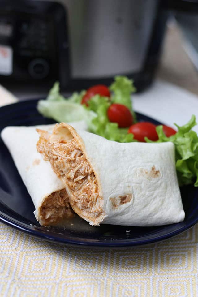 Slow cooker salsa chicken wraps on a blue plate with a side salad next to it