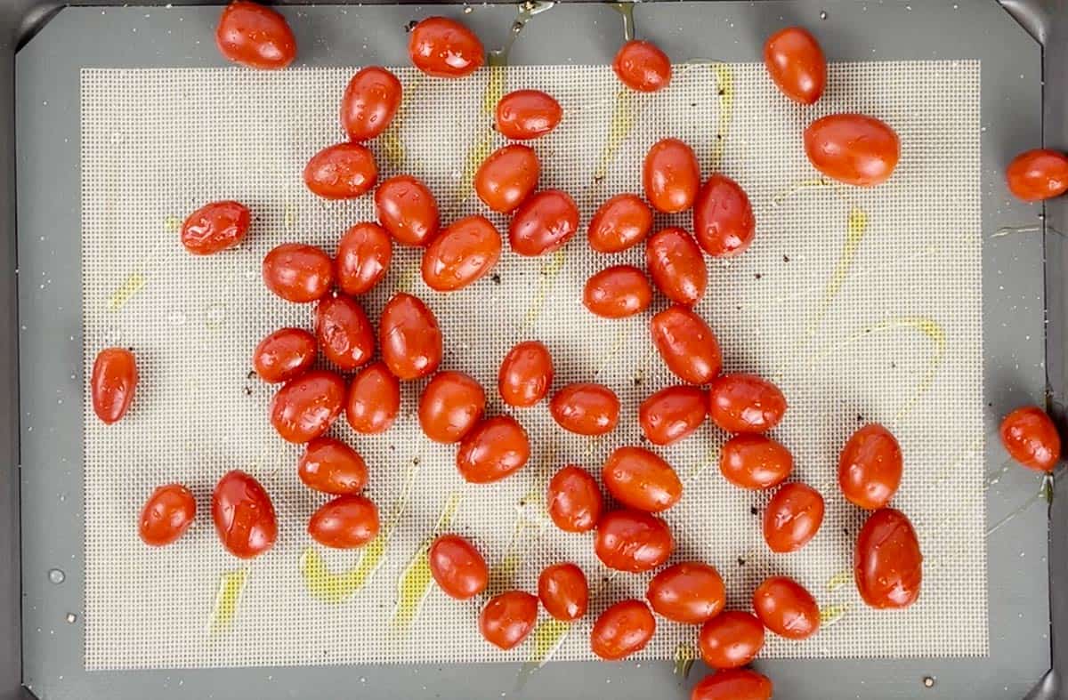 Cherry tomatoes on a cookie sheet with olive oil.