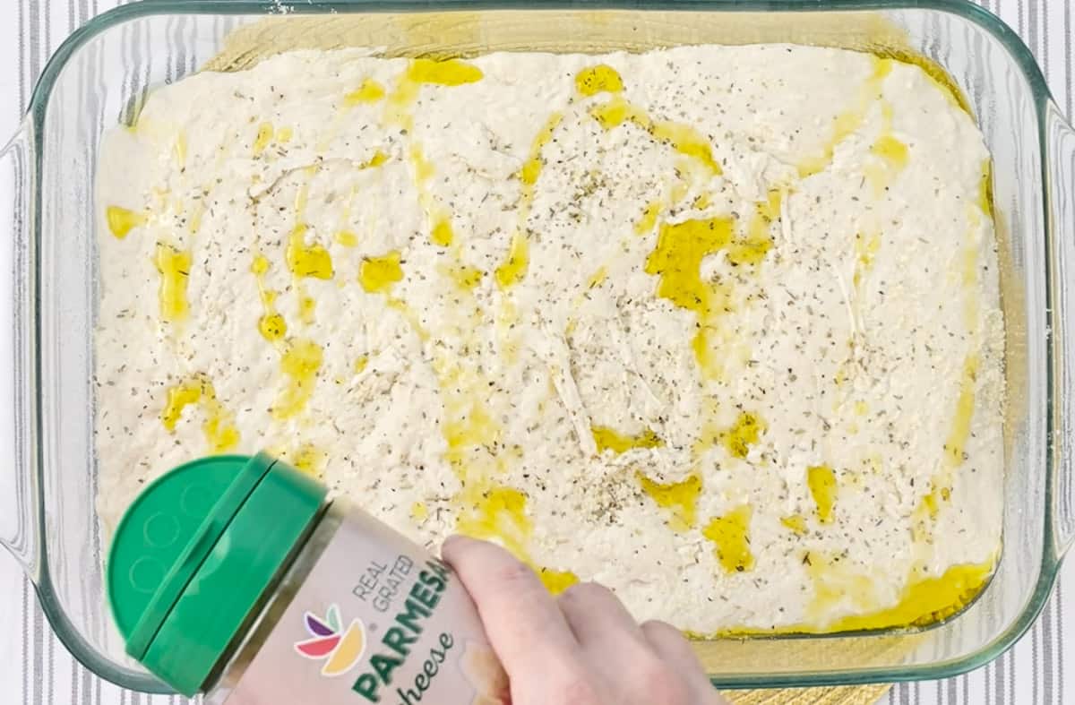 Sprinkling the bread dough with grated Parmesan cheese.