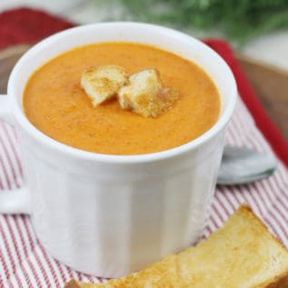 Roasted tomato soup in a white soup bowl with grilled cheese.