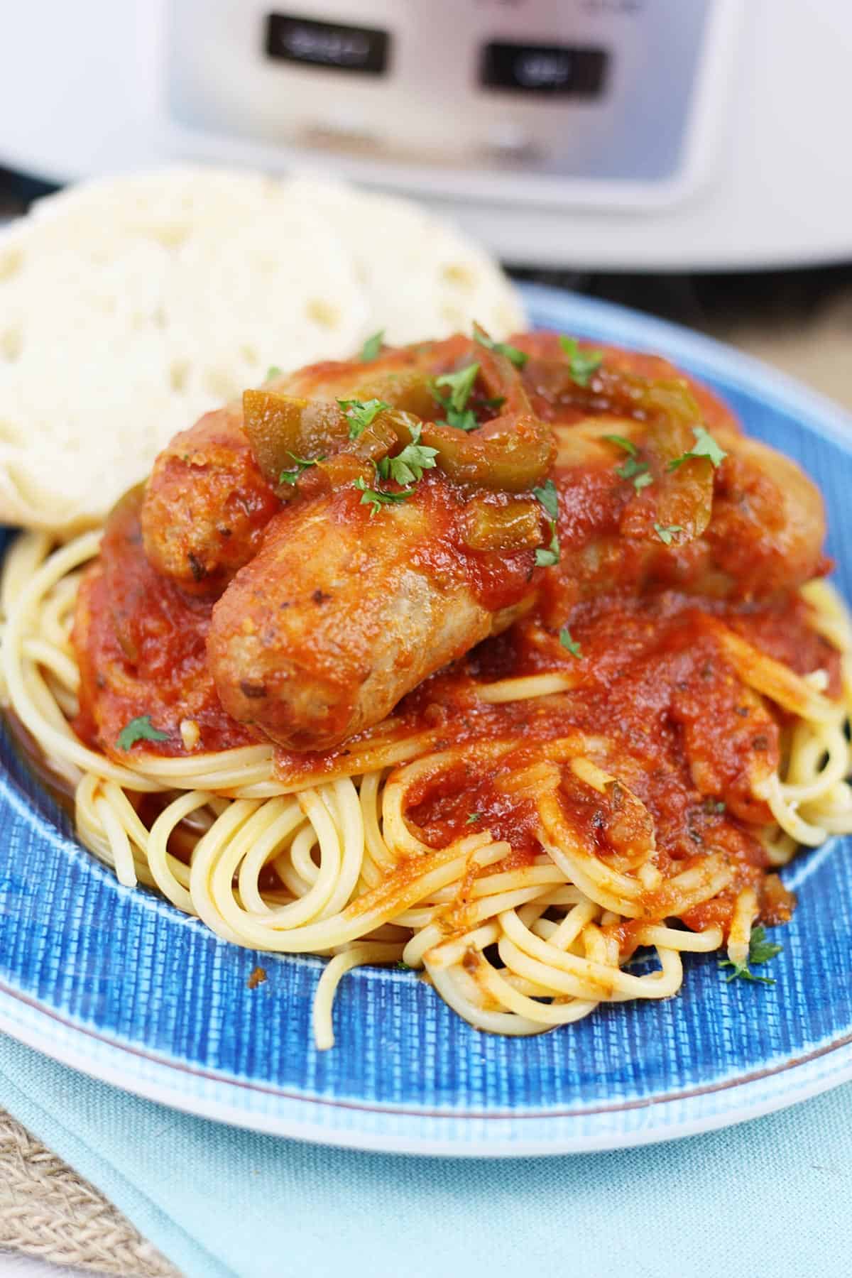 Cooked Italian sausage on a blue plate with spaghetti.
