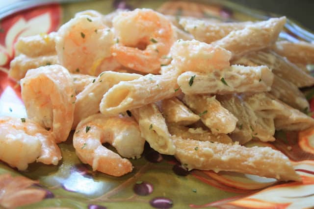 A serving of shrimp pasta on a green floral dinner plate.