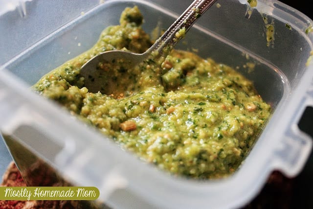 Pesto in a plastic container with a spoon.