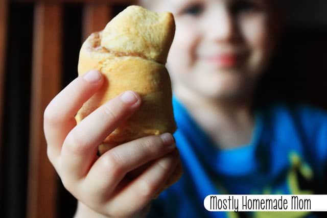 A kid holding up a crescent roll.