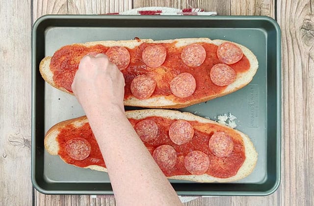 Spreading pizza sauce and pepperoni on sliced French bread