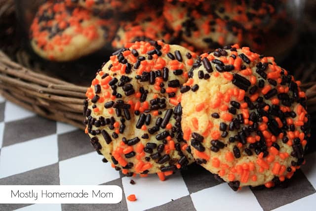 Two yellow cake mix cookies with orange and black sprinkles.