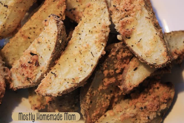 Parmesan potato wedges with seasoning on a plate.