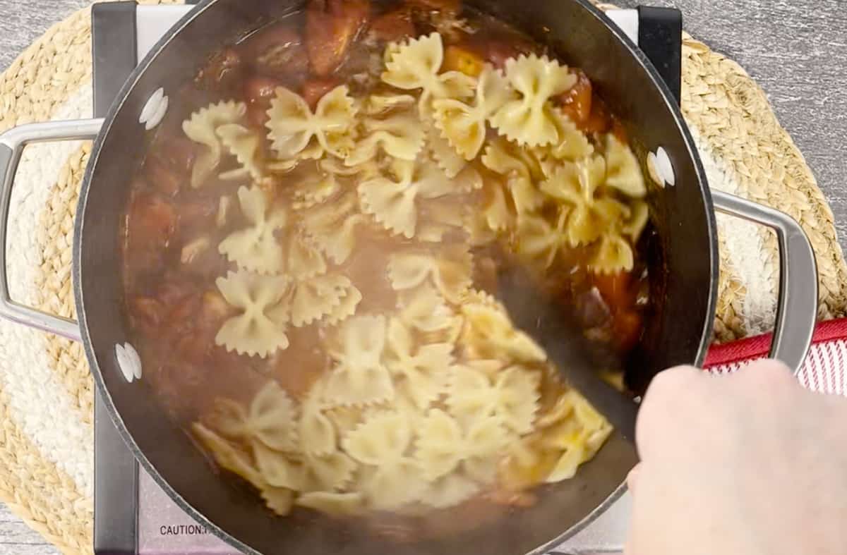 Stirring easy lasagna soup in a pot on a stove.