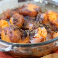 Sweet potato casserole in a glass baking dish with a wooden serving spoon