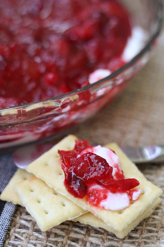 Crackers with a bit of cranberry dip on top next to a spreader