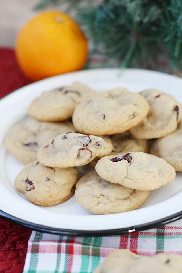 Cranberry orange cookies on a white plate with an orange in the background