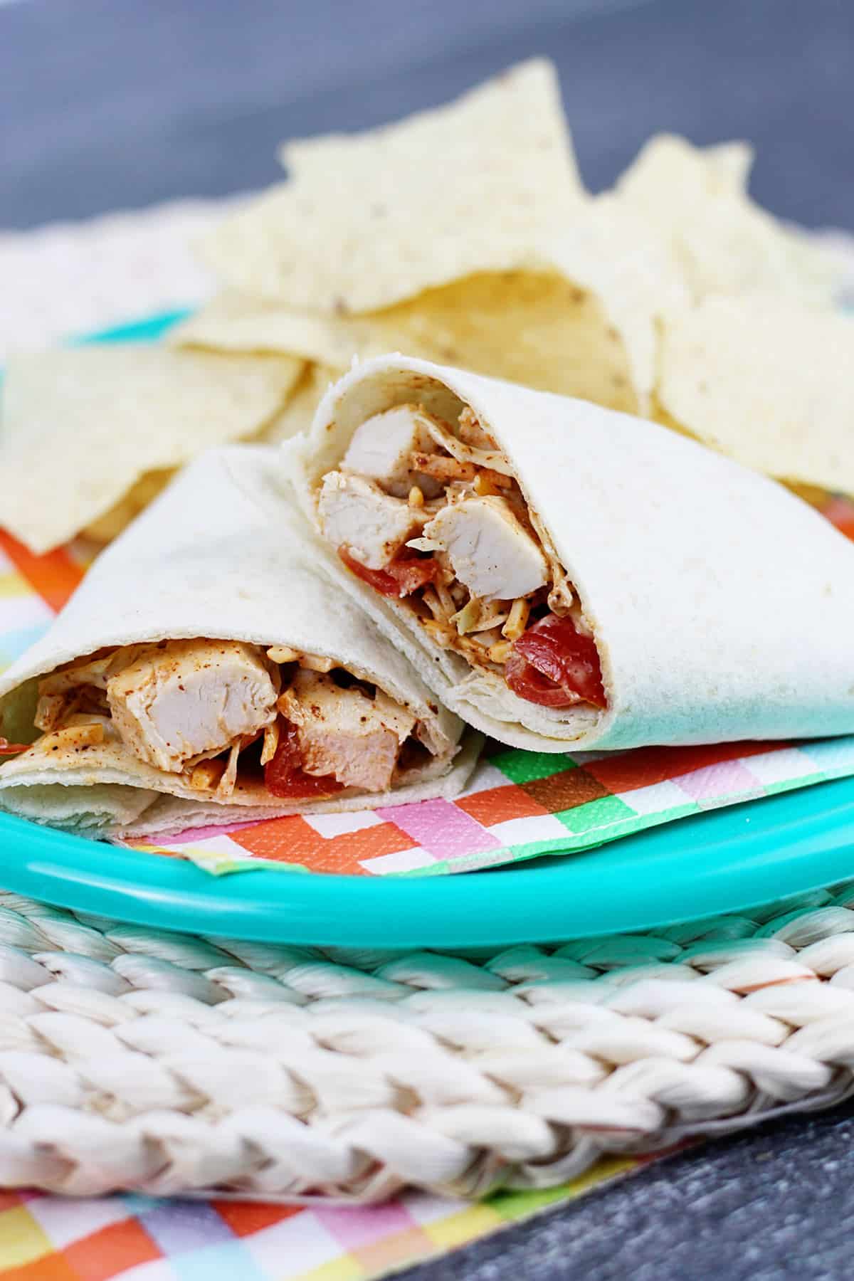 A Southwest chicken wrap sliced in half on a blue plate.