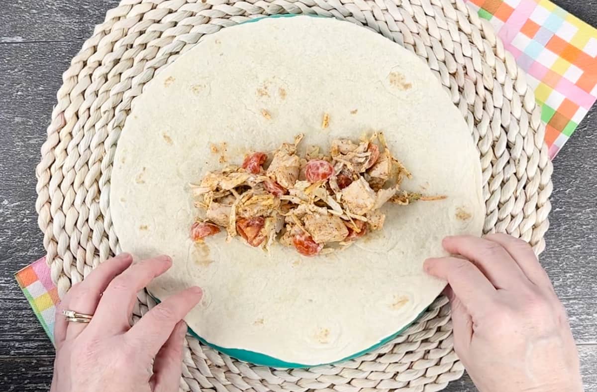 Rolling up a Southwest chicken wrap on a plate.