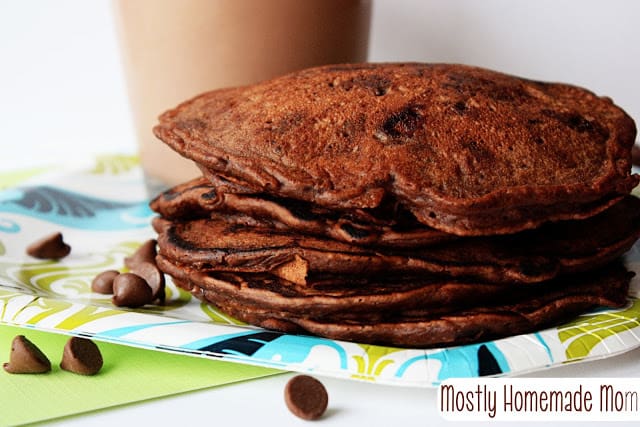 A stack of chocolate milk pancakes with a glass of chocolate milk.