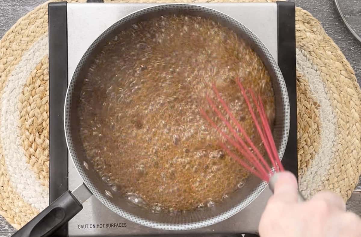 Whisking a sauce in a pan on the stove.