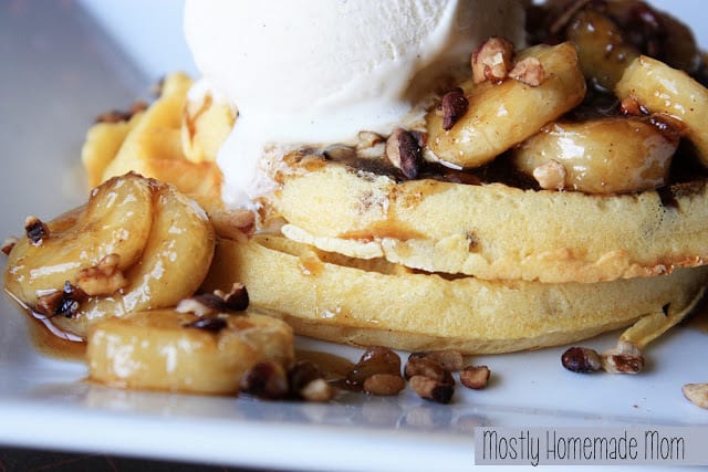 Bananas foster waffles on a white plate with ice cream.