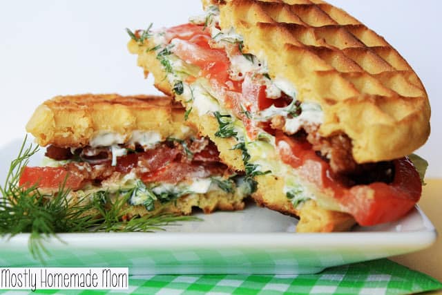 A waffle BLT sandwich sliced in half on a plate.