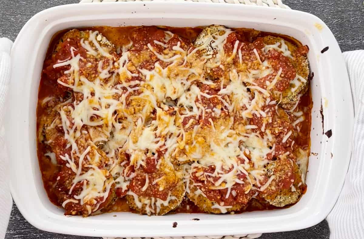 Serving baked eggplant parmesan in a white dish.
