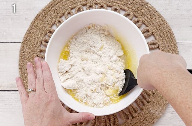 Mixing the sugar cookie dough in a white bowl with a black spatula