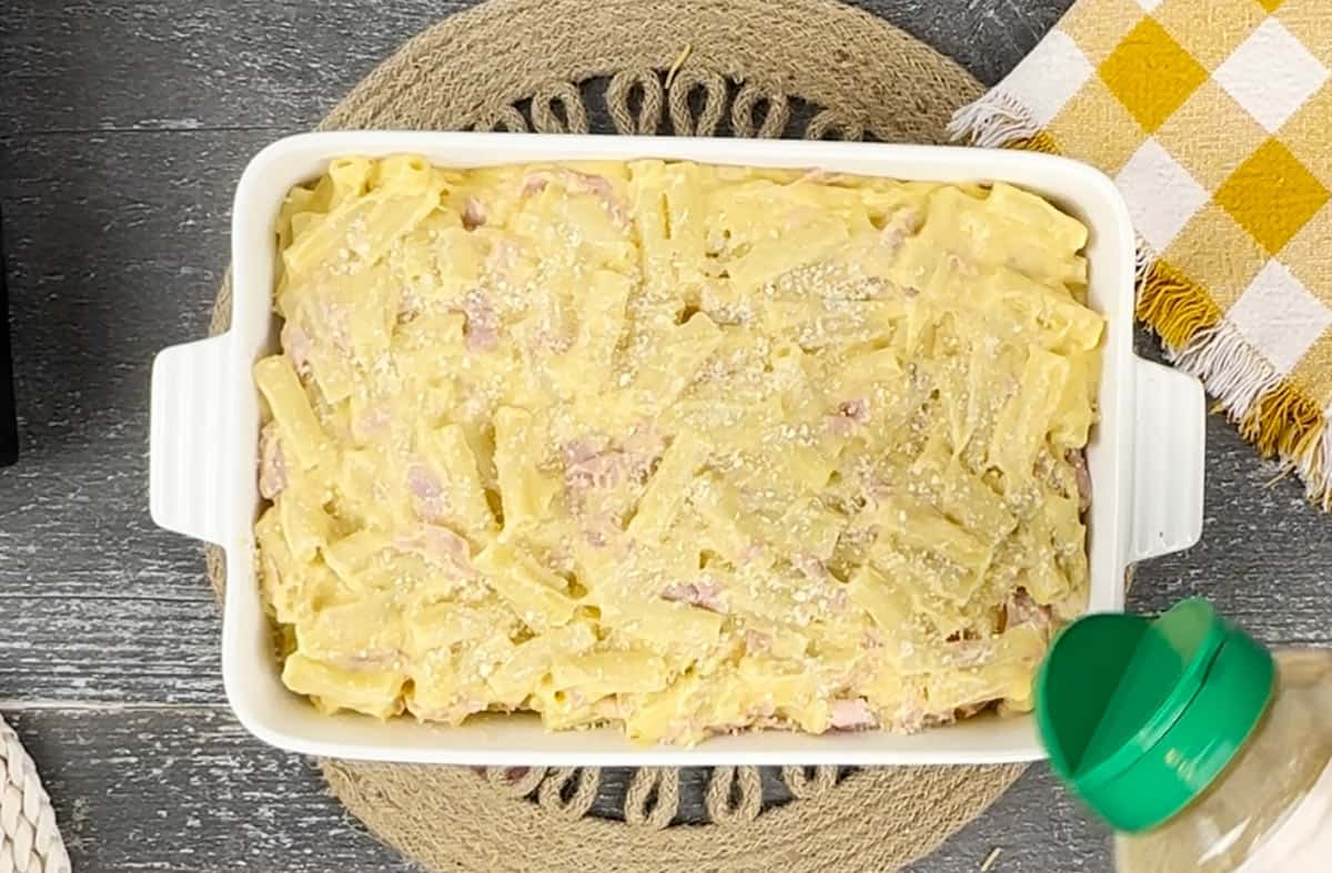 Sprinkling Parmesan cheese over casserole.