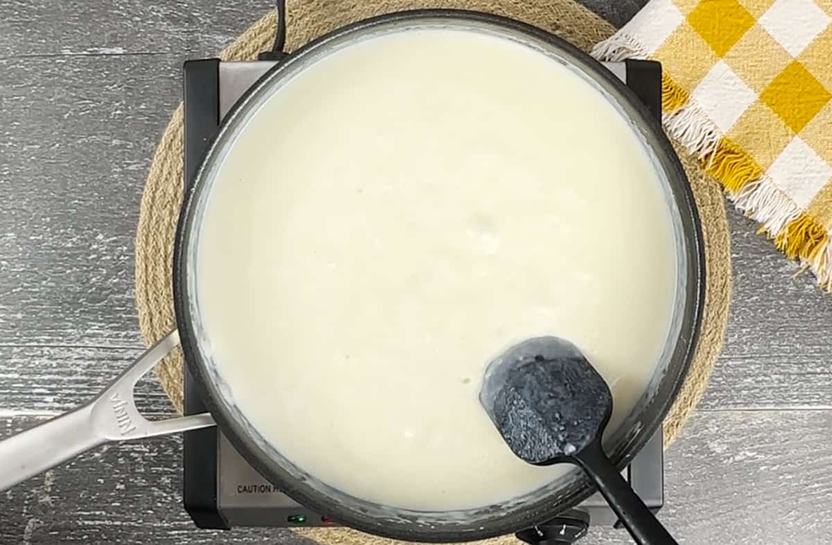 Boiling the milk mixture in a skillet with a spatula.