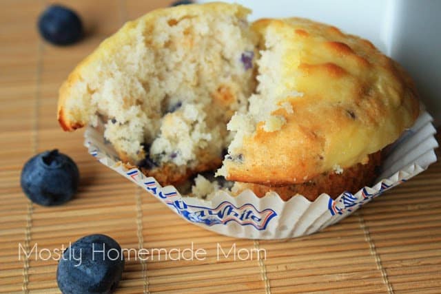 A halved blueberry cheesecake muffin in a paper liner.