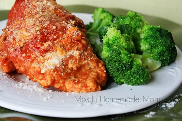 Slow cooker chicken parm on a white plate with broccoli.