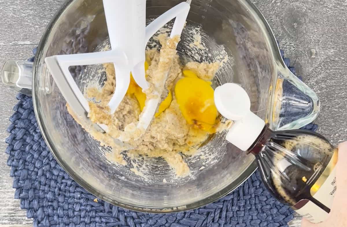 Adding vanilla extract to the ingredients in a stand mixer.