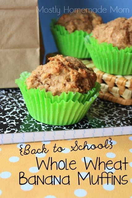 Whole wheat banana muffins in green muffin cups sitting on a notebook.