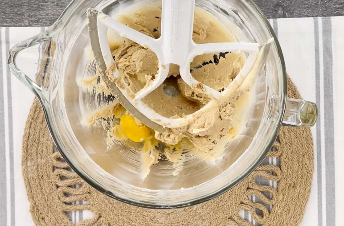 A glass stand mixer bowl blending cookie ingredients.