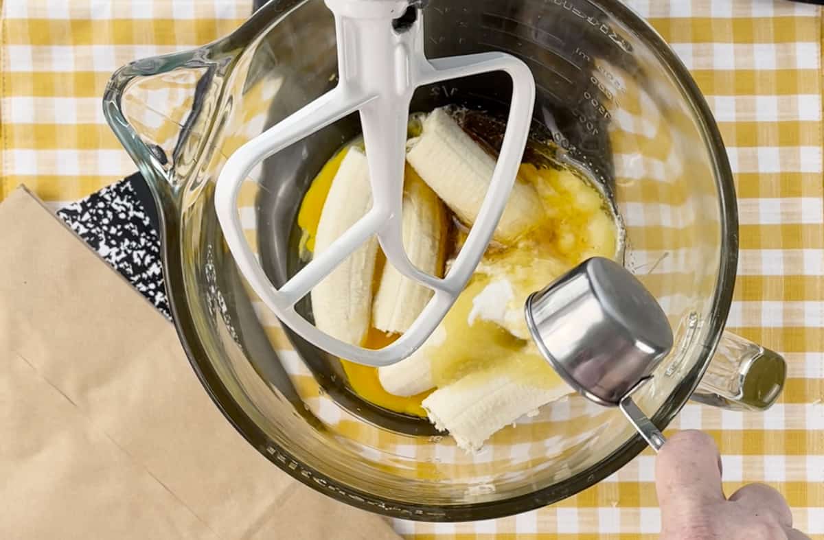 Bananas and eggs in a glass stand mixer bowl.