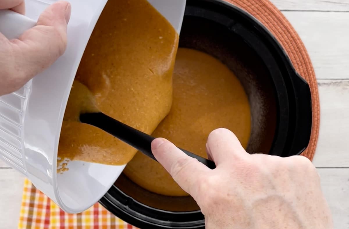 Pouring the pudding batter into a slow cooker.