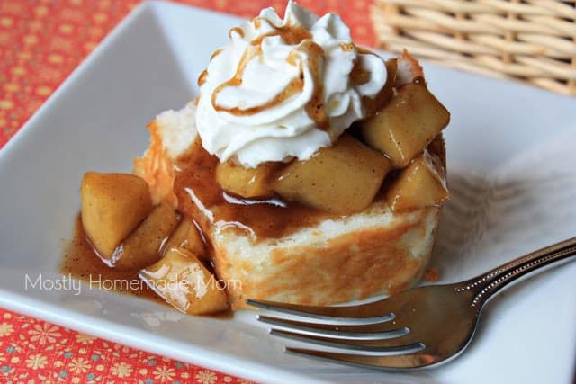 A serving of apple shortcake on a plate topped with whipped cream and caramel.
