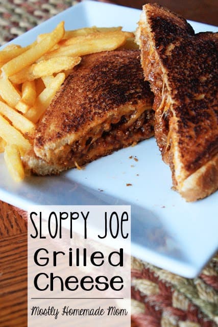 A sloppy joe grilled cheese sandwich cut into triangles on a white plate with fries.