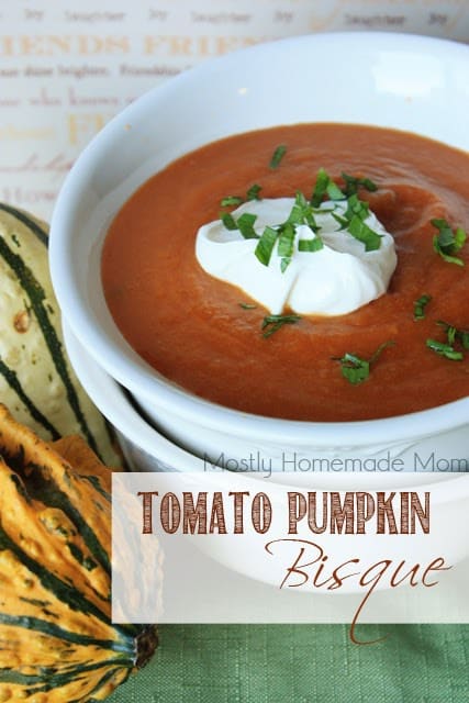 A bowl of tomato pumpkin bisque with sour cream.