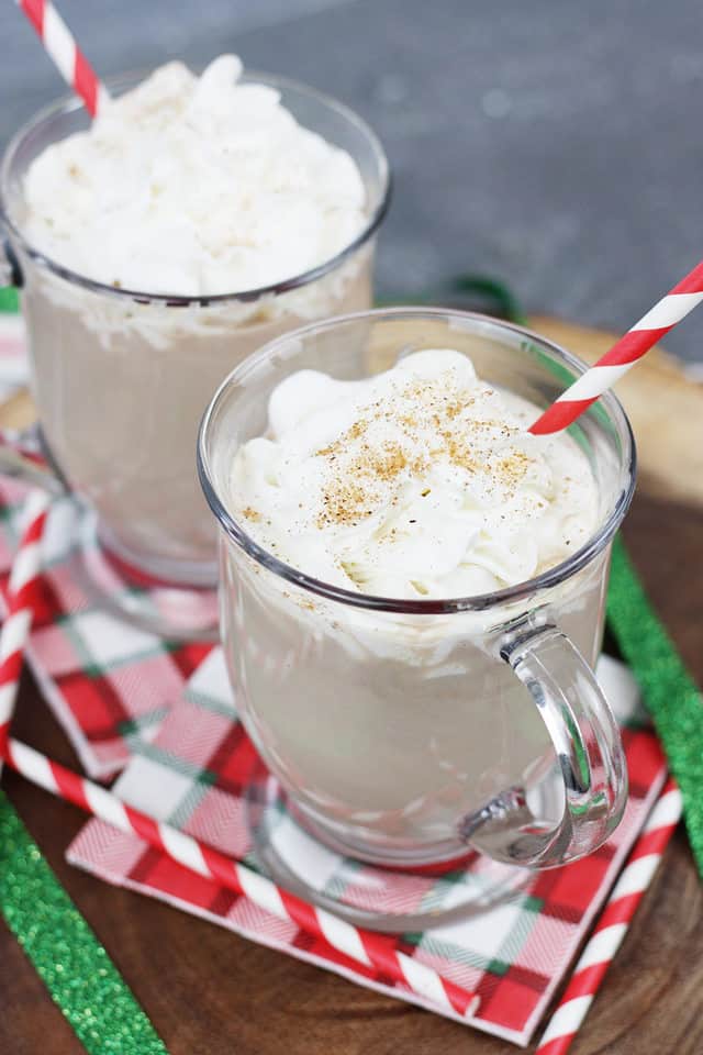 Two glass mugs filled with chocolate eggnog topped with whipped cream