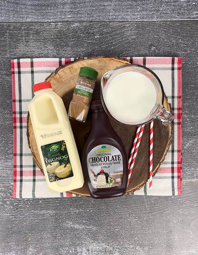 Ingredients for chocolate eggnog on a wood slice tray