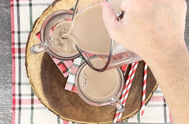 Pouring chocolate milk into two glass mugs